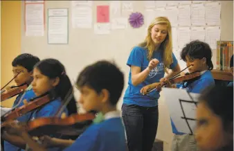  ?? Photos by Lea Suzuki / The Chronicle ?? Isabelle Gardner, an intern with the Enriching Lives Through Music program, helps fourthgrad­er Eli while teaching violin at Bahia Elementary in the Canal district of San Rafael.