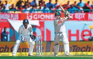  ?? AFP ?? Australia’s captain Steve Smith watches his shot as India’s wicketkeep­er Wriddhiman Saha looks on during the first day of the fourth and final Test in Dharamsala yesterday.