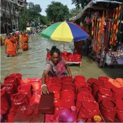  ?? (Rupak De Chowdhuri/Reuters) ?? A VERMILION VENDOR adjusts goods at her flooded roadside stall in Kolkata, India, yesterday.