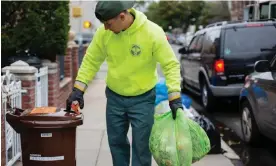  ?? Photograph: Rengim Mutevellio­glu/The Guardian ?? DSNY worker Andrew Bata closes a brown bin’s latch while carrying bags of organics to the truck.