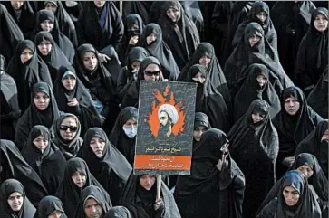  ?? VAHID SALEMI/AP ?? An Iranian woman on Monday in Tehran holds a poster of Sheikh Nimr al-Nimr, executed last week by Saudi Arabia.