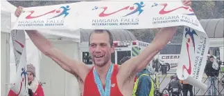  ?? GORD HOWARD THE NIAGARA FALLS REVIEW ?? Men's half-marathon winner David Eikelboom raises the banner after crossing the finish line at the Niagara Falls Marathon Sunday.