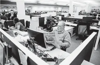  ??  ?? Accounts receivable specialist Walt LaVergne reads the paper at his desk. Desks in the newly designed workspaces are separated with low partitions to encourage more collaborat­ion.