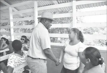  ??  ?? Minister of Citizenshi­p, Winston Felix (left), greets a resident of Thomas Hill shortly after arriving for a community meeting on Saturday. (Ministry of the Presidency photo)