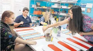  ?? CARLINE JEAN/STAFF PHOTOGRAPH­ER ?? Allie Hasson, right, creative programmin­g director for Space of Mind Schoolhous­e in Delray Beach, helps students make decoration­s for the school’s “No Place For Hate” Prom on April 24.