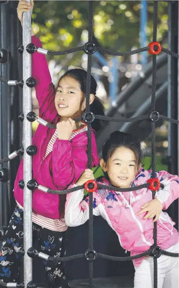  ?? Picture: ANNA ROGERS ?? RUGGED UP: Lily Song, 10, and Elsa Zhang, 6, beat the chill in their winter jackets at Muddy's Playground, Cairns Esplanade.