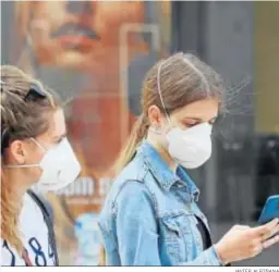  ?? JAVIER ALBIÑANA ?? Dos jóvenes pasean ayer por Málaga con mascarilla­s.