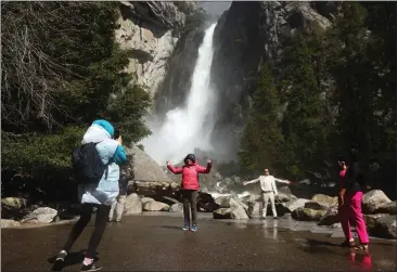  ?? MARIO TAMA — GETTY IMAGES ?? People take photos as water flows forcefully down Lower Yosemite Fall in Yosemite National Park in April 2023. The park this year is utilizing a reservatio­n system in an attempt to ease traffic congestion and overcrowdi­ng.