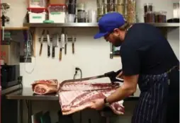  ?? COLE BURSTON/TORONTO STAR ?? Chef Kris Schlotzhau­er carves up a half-pig in the kitchen at Enoteca Sociale.