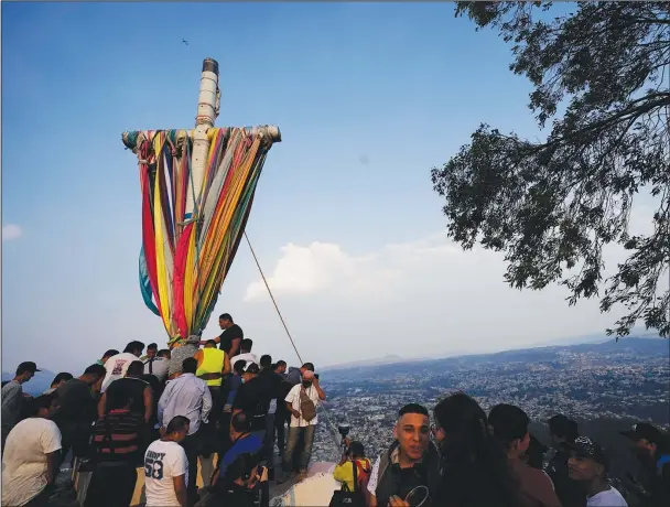  ?? (Ap/eduardo Verdugo) ?? People gather around a heavy, wooden cross Monday before lowering it from the hilltop as part of celebratio­ns marking the Day of the Cross in the Santa Cruz Xochitepec neighborho­od of Mexico City.