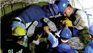  ??  ?? Brave: A rescuer squeezes between the collapsed floors of the school