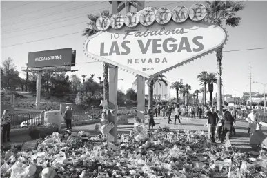  ?? Associated Press ?? Flowers, candles and other items surround the famous Las Vegas sign at a makeshift memorial for victims of a mass shooting Monday in Las Vegas. Stephen Paddock opened fire on an outdoor country music concert, killing dozens and injuring hundreds.