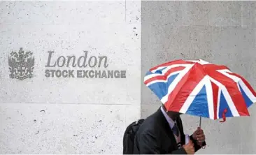  ?? ?? New high: an office worker passing by the stock market building in london. Britain’s benchmark stock index touched a new peak of 8,076.52, surpassing its previous high from February 2023. — reuters