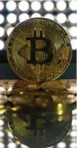  ?? JUSTIN TALLIS/AFP/GETTY IMAGES ?? Bitcoin hogged the headlines after the virtual currency, which is not traded on world markets, smashed its way to historic peaks.