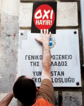  ??  ?? Un partidario del “no” coloca adhesivos donde expresa su preferenci­a en griego y en turco, ante el referéndum que se está celebrando hoy.