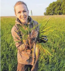  ?? FOTOS: PHILIPP GRUBER ?? Mit Handschuhe­n und einem Büschel Grün hält Barbara Gruber ein von der Drohne geortetes Rehkitz und bringt es in Sicherheit.