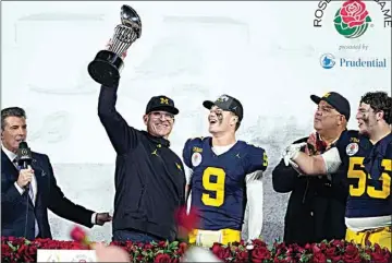  ?? MARK J. TERRILL / AP ?? Michigan coach Jim Harbaugh holds the winner’s trophy next to quarterbac­k J.J. McCarthy (9) and defensive lineman Mason Graham (55) after a win over Alabama in Monday’s Rose Bowl in Pasadena.