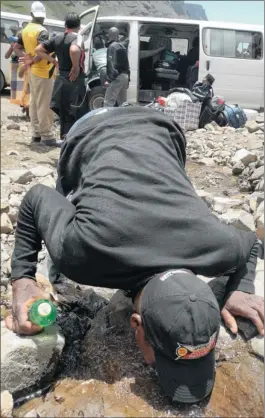  ?? PICTURES: YUSUF OMAR ?? NO GARAGE STOPS: A man quenches his thirst at a stream along the Sani Pass.