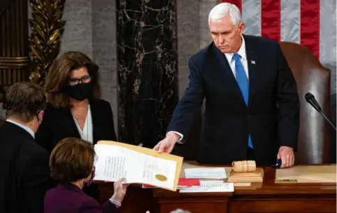  ?? SAUL LOEB/AP ?? Then-vice president Mike Pence handed the electoral certificat­e from the state of Arizona to Senator Amy Klobuchar, as he presided over a joint session of Congress as it convened to count the Electoral College votes cast in the 2020 presidenti­al election, following an attack on the US Capitol.