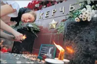  ?? AP PHOTO ?? A girl lights a candle in memory of the victims of Wednesday’s attack on a vocational college in Kerch, Crimea, at the memorial stone with the word Kerch in the Alexander Garden near the Kremlin in Moscow Thursday.