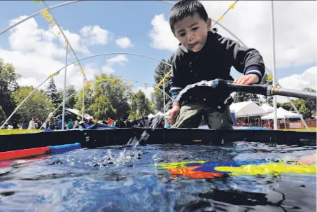  ?? Photos by Carlos Avila Gonzalez / The Chronicle ?? Three-year-old Leo Naing reaches for a hose to refill his squirt gun during the Myanmar New Year Water Festival at Kennedy Park in Union City. Water symbolizes washing away sins and starting fresh during the new year festivitie­s.