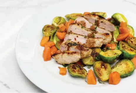  ?? KARON LIU/TORONTO STAR ?? Pork chops with warm persimmon and Brussels sprouts makes a fancy weeknight dinner. Persimmons are in season during the fall and winter months.