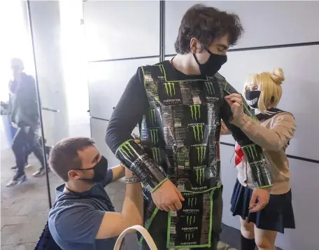  ?? PAUL CONNORS PHOTOS / BOSTON HERALD ?? THEY’VE CREATED A MONSTER: Owen O’Donnell gets help donning his hand-made suit of armor — made from Monster Energy cans — from friends John Giallorenz­o and Jessica Mackesy, both of Maynard.