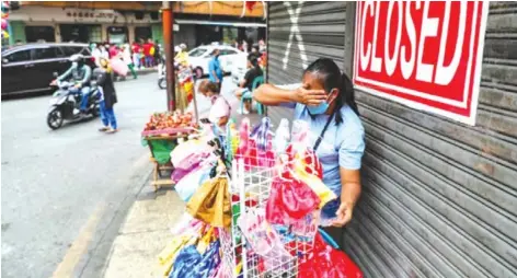  ?? (Jonathan Cellona/ABS-CBN News photo) ?? People pass by closed shops, some of which were affected by the ongoing COVID-19 pandemic, in Binondo, Manila during Chinese New Year on February 1, 2022.