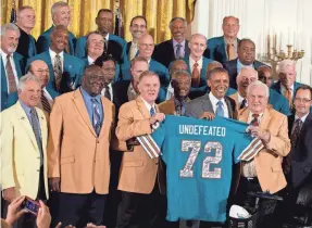  ?? AP FILE PHOTO BY JACQUELYN MARTIN ?? 1972 quarterbac­k Bob Griese holds a signed Dolphins jersey with President Barack Obama and coach Don Shula in 2013.