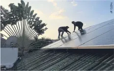  ??  ?? SOLAR SOLUTION: Staff from an alternativ­e energy company install solar rooftop panels at a house in Bangkok.