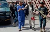  ?? — AFP ?? A member of the Afghan security forces and a medical staff assist an injured man walk to a hospital following a bomb blast in Jalalabad on Monday.