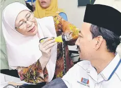  ?? — Bernama photo ?? Dr Wan Azizah checks the eyes of Mohd Zawawi at the health screening programme.