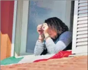  ?? REUTERS ?? A woman recites a prayer with a rosary in her hand in the window of n
her home in Grosseto, Italy.
