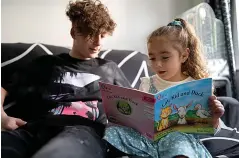  ??  ?? Safe... Aymen, 15, helps sister Hala, four, to read at the family’s new home in the UK, far from the bombs and bullets of wartorn Aleppo in Syria