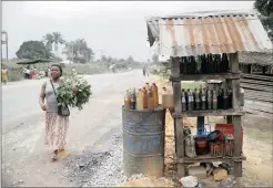  ?? PHOTO: REUTERS ?? A woman walks past a shed displaying bottles containing petrol for sale along a road in Ikot-Ada-Udo community in Nigeria’s Akwa Ibom state. The writer says 90 percent of the population lives in poverty with 70 percent in abject poverty.