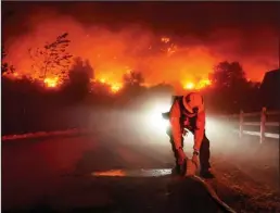  ?? KENT NISHIMURA/LOS ANGELES TIMES ?? Firefighte­rs battle the Bond fire along Silverado Canyon Road in Silverado on Dec. 3, 2020.