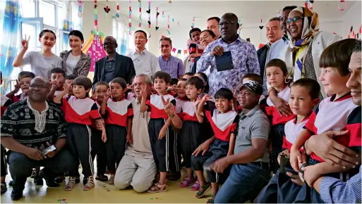  ??  ?? Officials of various countries and internatio­nal organizati­ons pose for a group photo with kindergart­en kids in Hotan County, Xinjiang.