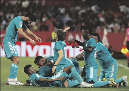  ?? AP PHOTO/ANGEL FERNANDEZ ?? Real Madrid’s Karim Benzema celebrates with teammates after scoring his side’s third goal during a Spanish La Liga soccer match between Sevilla and Real Madrid at the Ramon Sanchez Pizjuan stadium, in Seville, Spain, on Sunday.