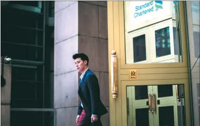  ?? ANTHONY WALLACE / AFP ?? A man leaves the Standard Chartered bank building in the Central district of Hong Kong.