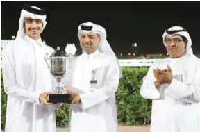  ?? PICTURES: Juhaim ?? Al Shaqab Equestrian Facility Expert Majid Nasser al-Kaabi (centre) presents the owner’s trophy to Khalifa bin Sheail al-Kuwari after Scudding won the Qatar Cup at the Qatar Racing and Equestrian Club’s Al Rayyan Park yesterday.