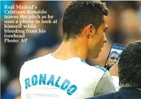  ??  ?? Real Madrid’s Cristiano Ronaldo leaves the pitch as he uses a phone to look at himself while bleeding from his forehead Photo: AP