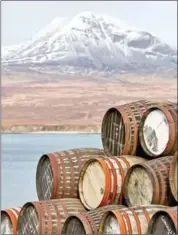  ?? ANDY HASLAM/THE NEW YORK TIMES ?? Barrels at Bunnahabha­in Distillery, with the ‘Paps of Jura’ hills in the distance, in Islay, Scotland, on April 24.