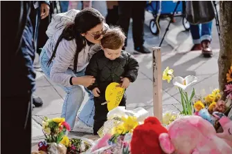  ?? Carlos Avila Gonzalez/The Chronicle ?? Silvia Olivar places flowers with Sullivan Clerico during a vigil for those killed on West Portal when a woman crashed into a bus stop on Monday. A baby whose parents and brother were killed has died.