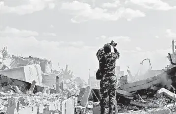  ?? LOUAI BESHARA/GETTY-AFP ?? A Syrian soldier inspects the wreckage of a building that was targeted during the U.S.-led missile attack early Saturday.