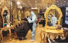  ?? AP ?? Hairdresse­rs in protective gear at a salon in New Delhi on Friday, as businesses and shops reopened in many states.