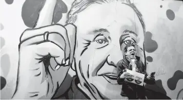  ?? LEONARDO MUNOZ AP ?? A supporter of Rodolfo Hernandez, the presidenti­al candidate dubbed “Colombia’s Trump,” stands in front of a mural of the candidate.