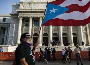  ?? AP ?? HOPING FOR CHANGE: A demonstrat­or carries a Puerto Rican flag outside the Capitol this week in San Juan, Puerto Rico. The protests have died down with the appointmen­t of a new governor, Wanda Vazquez, but not all tension has dissipated.