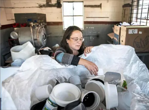  ?? Alexandra Wimley/Post-Gazette ?? Glass artist Ashley McFarland, founder of nonprofit Reimagined Recycling, sorts plastic into bins in a warehouse in Larimer.