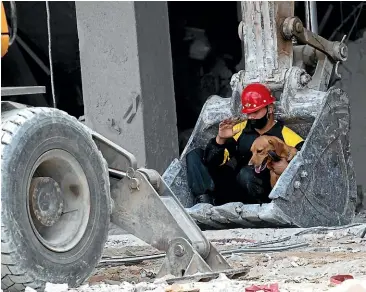  ?? AP ?? A rescue worker and his search dog are transporte­d on the shovel of an earthmover to search for survivors at the site of a deadly explosion that destroyed the five-star Hotel Saratoga in Old Havana.