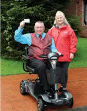  ?? ?? Passed! Les Fernie holds up a scooter ‘licence’ with Shopmobili­ty administra­tor Karen Miller